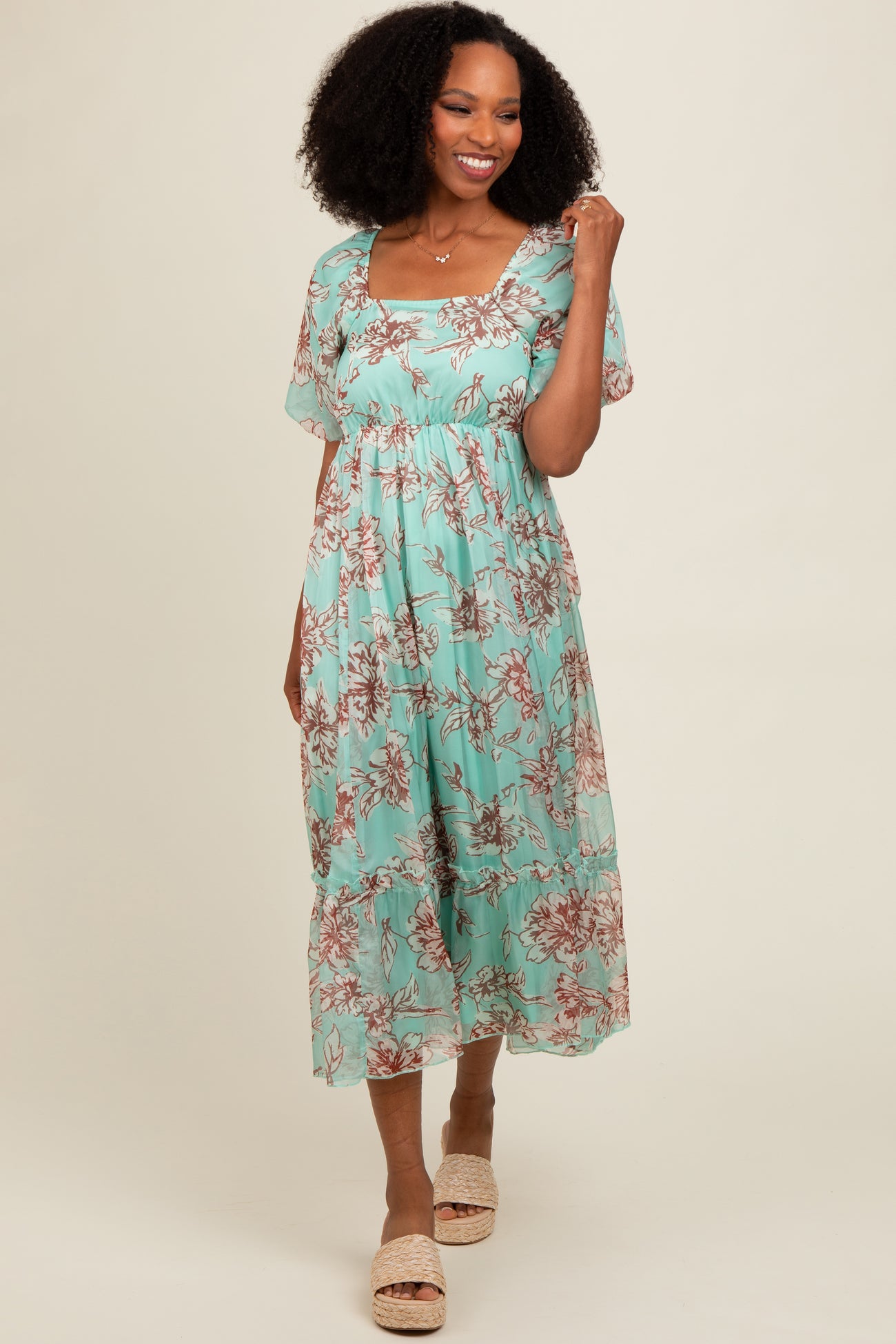 woman wearing a mint green floral maxi dress with short flutter sleeves and a square neckline
