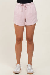 woman wearing light pink athletic shorts with an elastic waistband and drawstring, paired with white sneakers