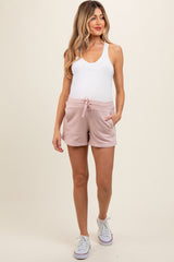 woman wearing a white tank top and pink maternity shorts with pockets and a drawstring, showcasing a baby bump