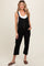 woman wearing a black maternity jumpsuit with buttons and pockets, standing and showing her baby bump