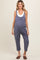 woman wearing a navy blue maternity jumpsuit with buttons and a white tank top underneath, showing a baby bump