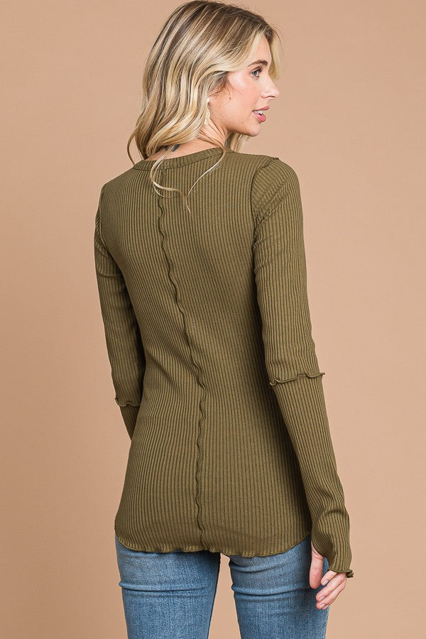 woman wearing an olive green ribbed long sleeve top with a curved hem and relaxed fit, styled with skinny jeans