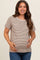 woman wearing a light brown and cream striped maternity top and holding her baby bump