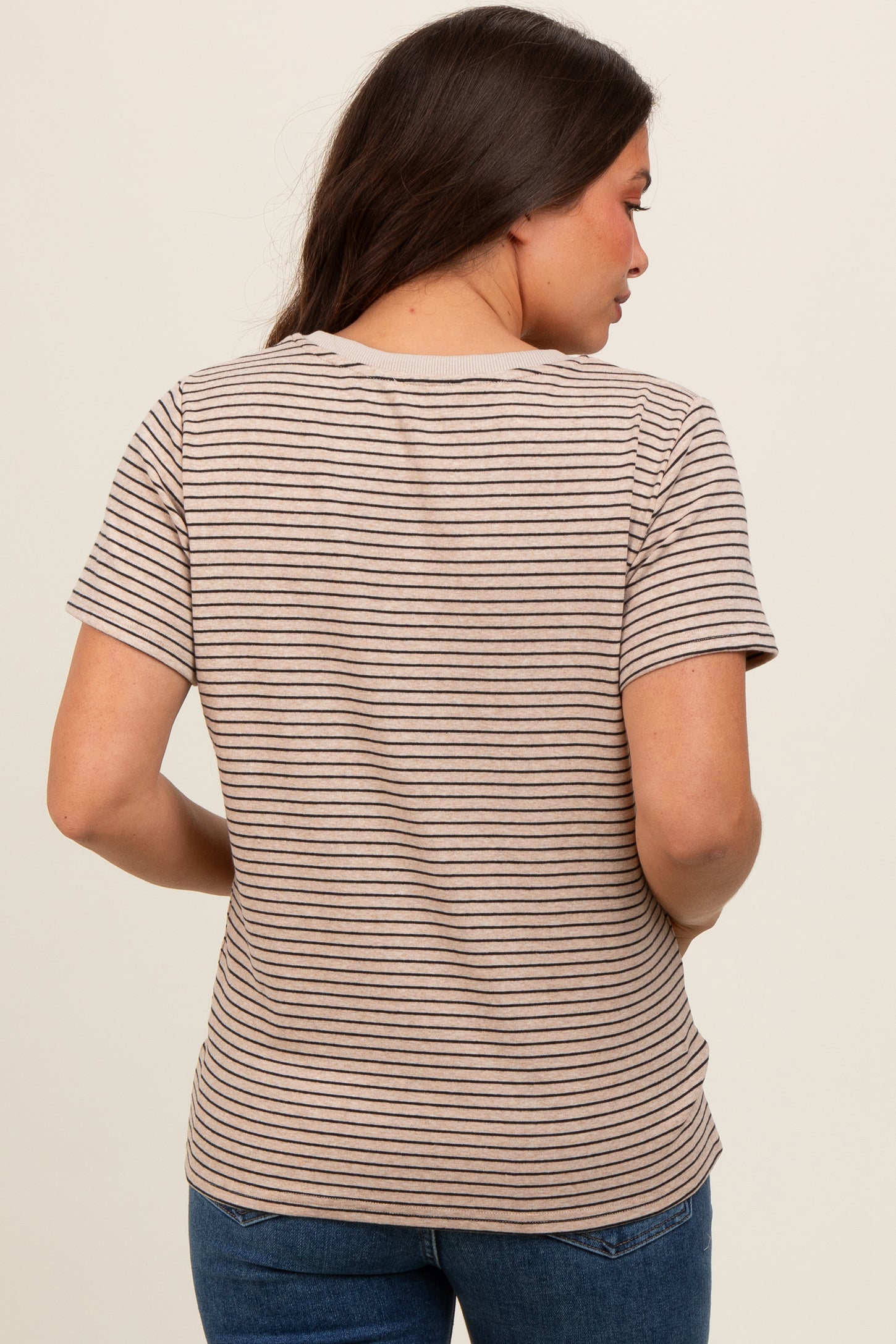 woman wearing a light brown striped maternity top, viewed from the back, with short sleeves and a relaxed fit