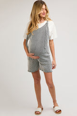 woman wearing a striped maternity romper and holding her baby bump