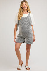 woman wearing a striped maternity romper with pockets and a white t-shirt underneath, showcasing a baby bump