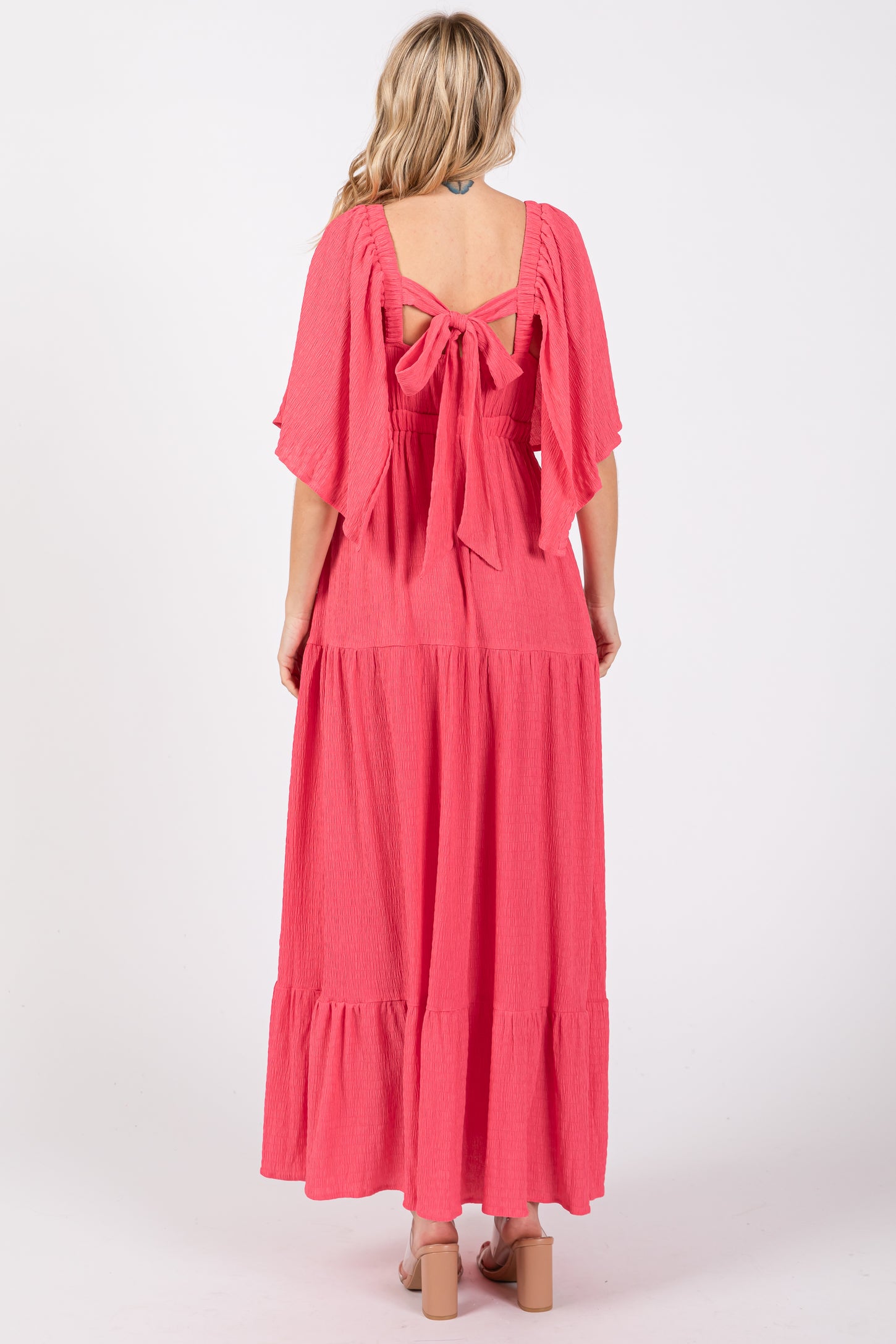 woman wearing a pink maxi dress with a tie-back detail and flutter sleeves