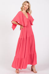 woman wearing a coral maxi dress with flutter sleeves and a tiered skirt