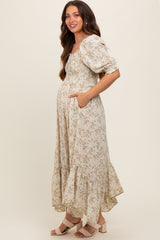 woman wearing a floral print maternity dress with puff sleeves and pockets, showcasing her baby bump.