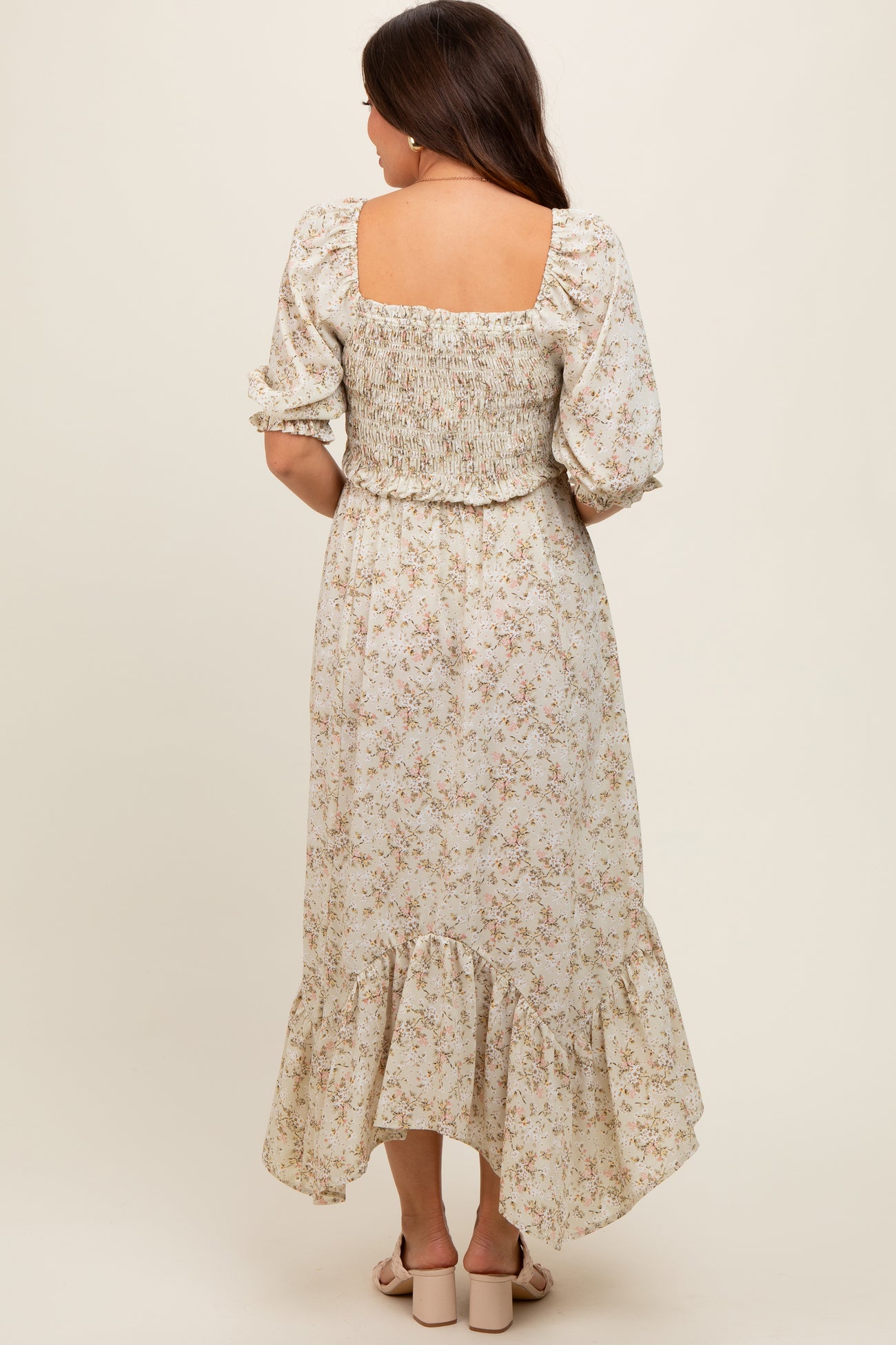 woman wearing a floral maternity dress with a smocked bodice and puff sleeves, showcasing a flowing hemline from the back