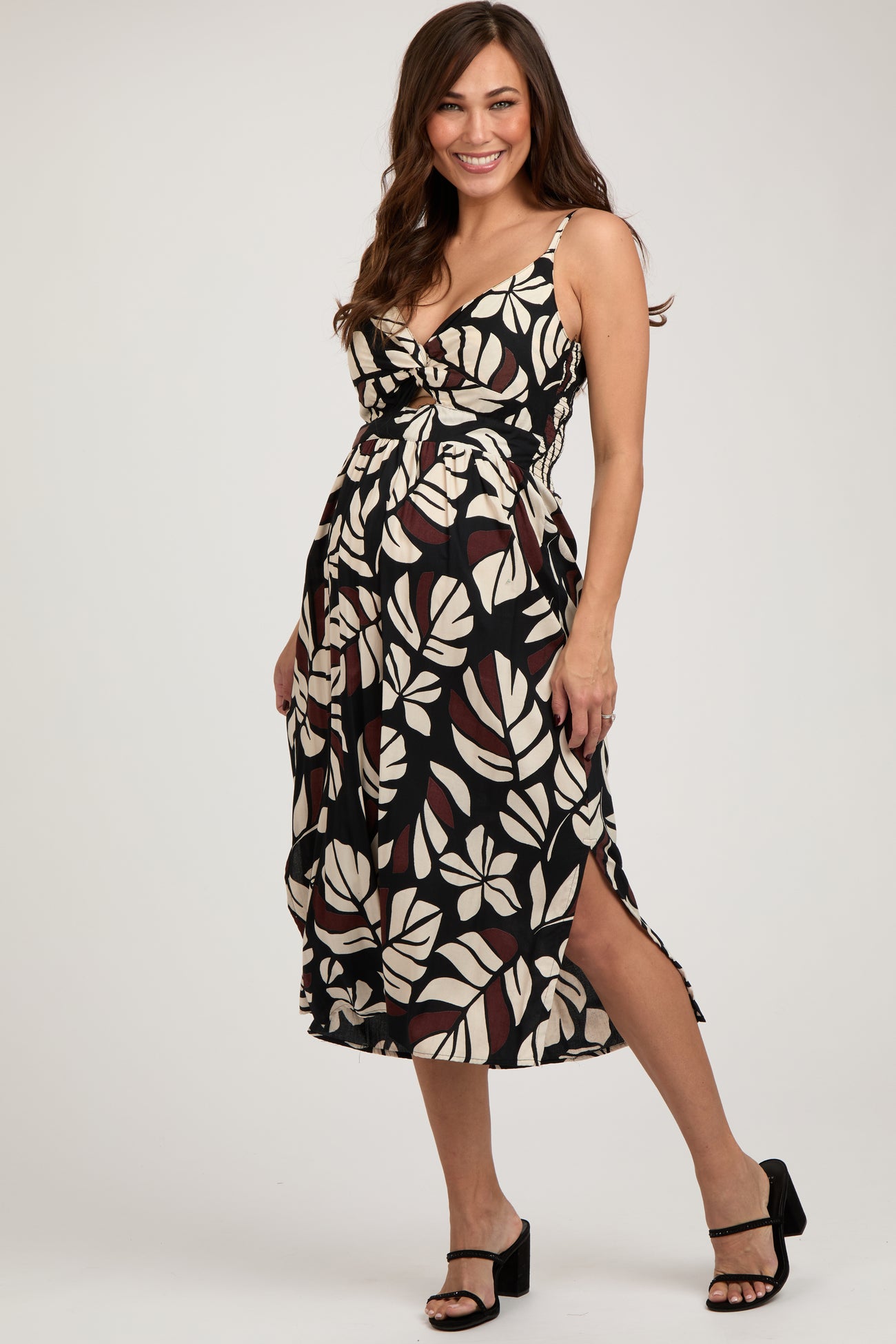 woman wearing a black and cream floral maternity dress with a knot detail and side slits, showing her baby bump