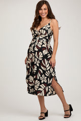 woman wearing a black and cream floral maternity dress with a knot detail and side slits, showing her baby bump