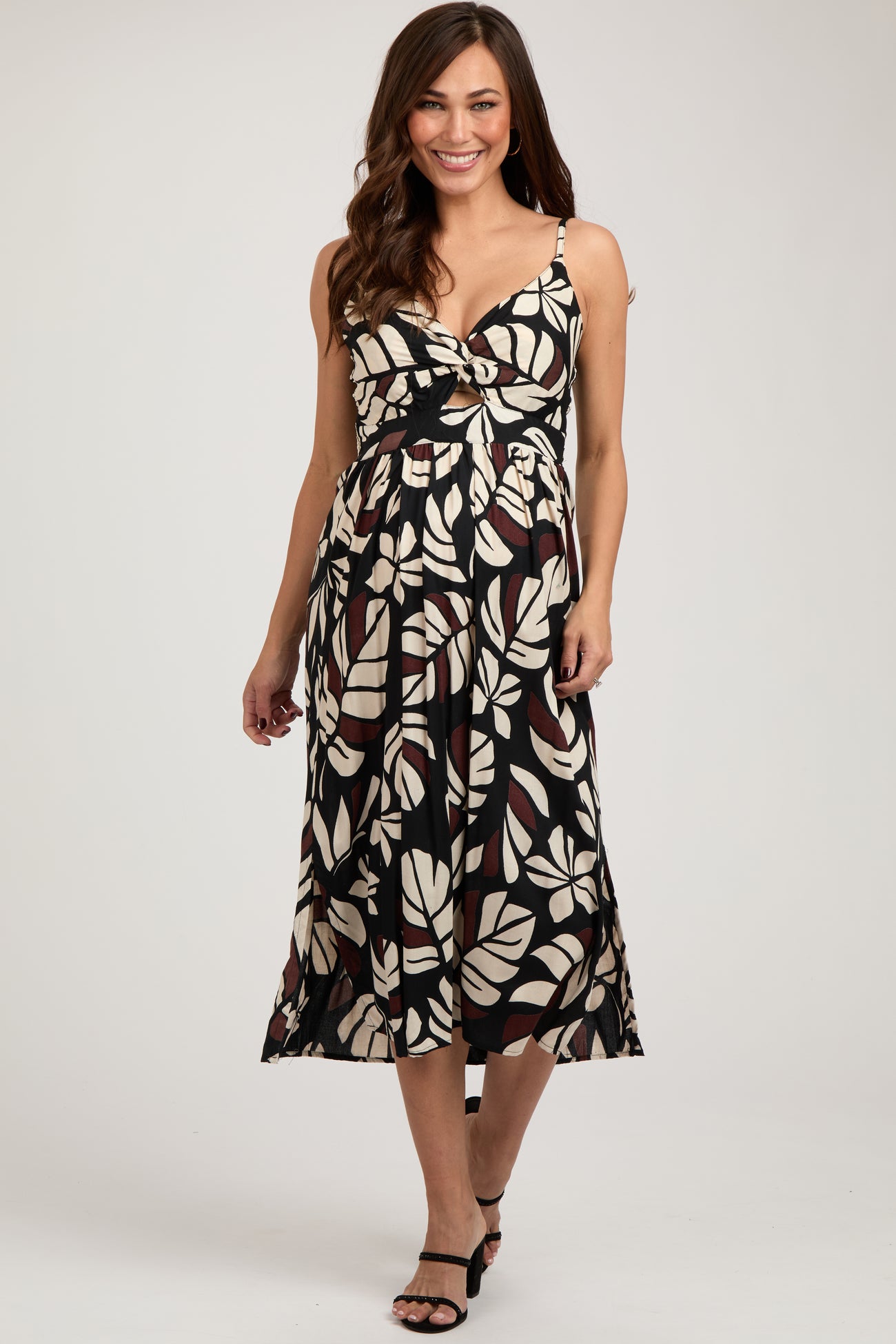 woman wearing a black and cream leaf print maternity dress with a cutout detail and a flowy skirt