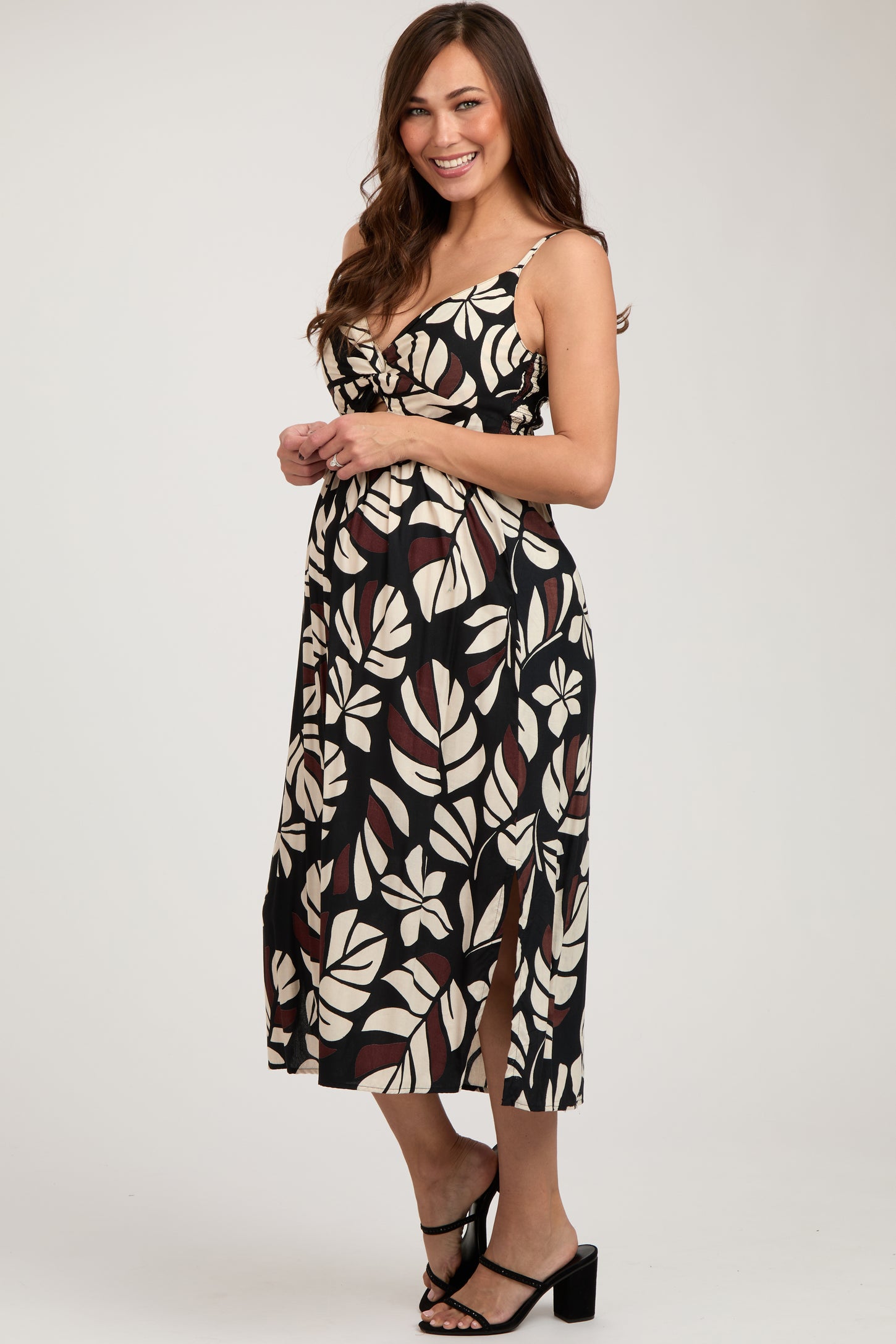 woman wearing a black and cream floral print maternity dress with slits, showing her baby bump