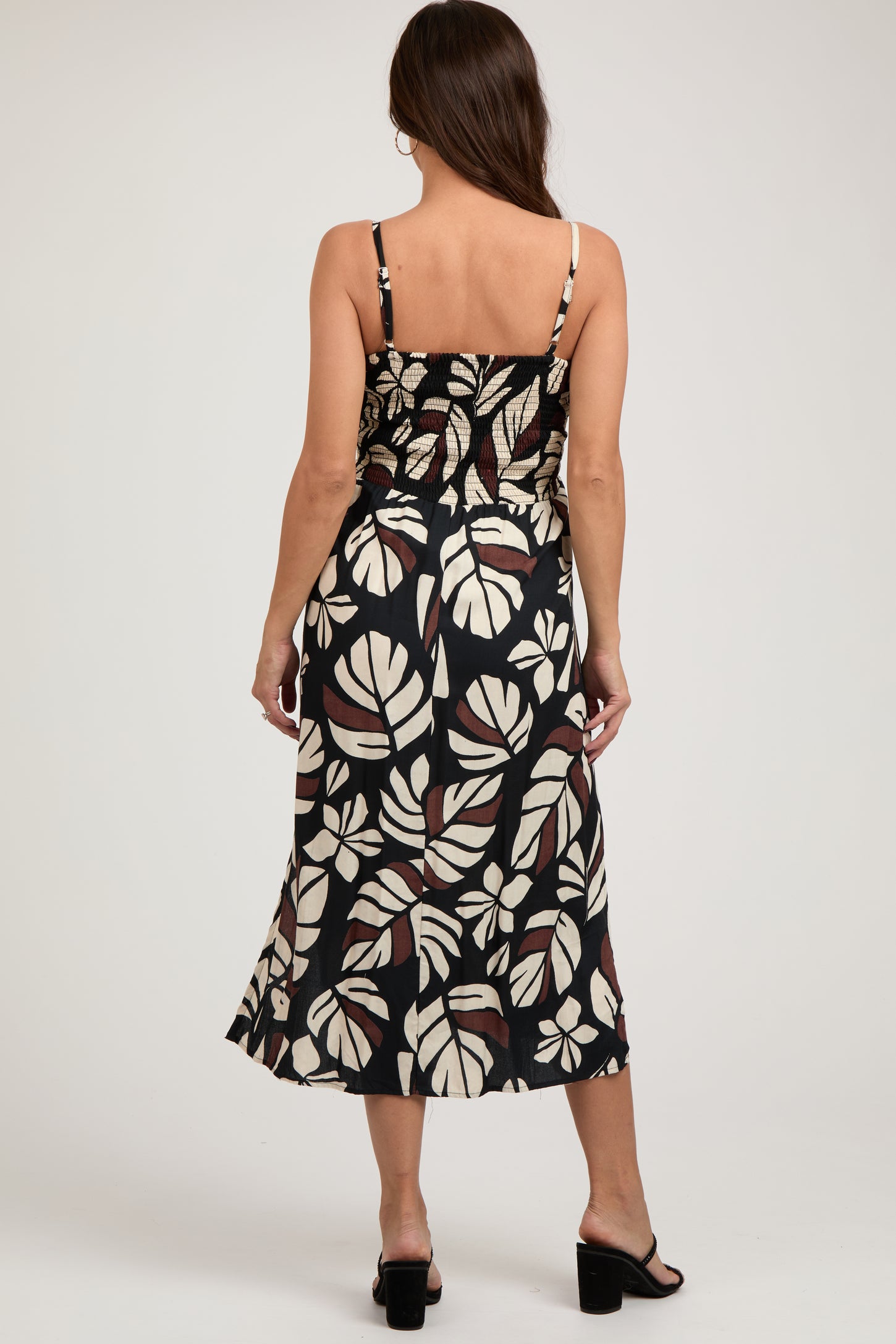 woman wearing a black and white floral print maternity dress with spaghetti straps and a fitted bodice