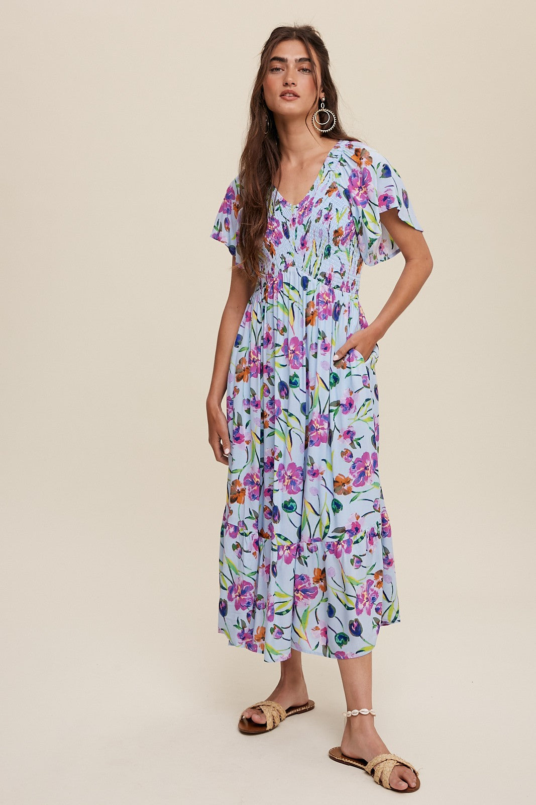 woman wearing a light blue floral maxi dress with flutter sleeves and pockets