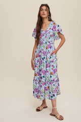 woman wearing a light blue floral maxi dress with flutter sleeves and pockets