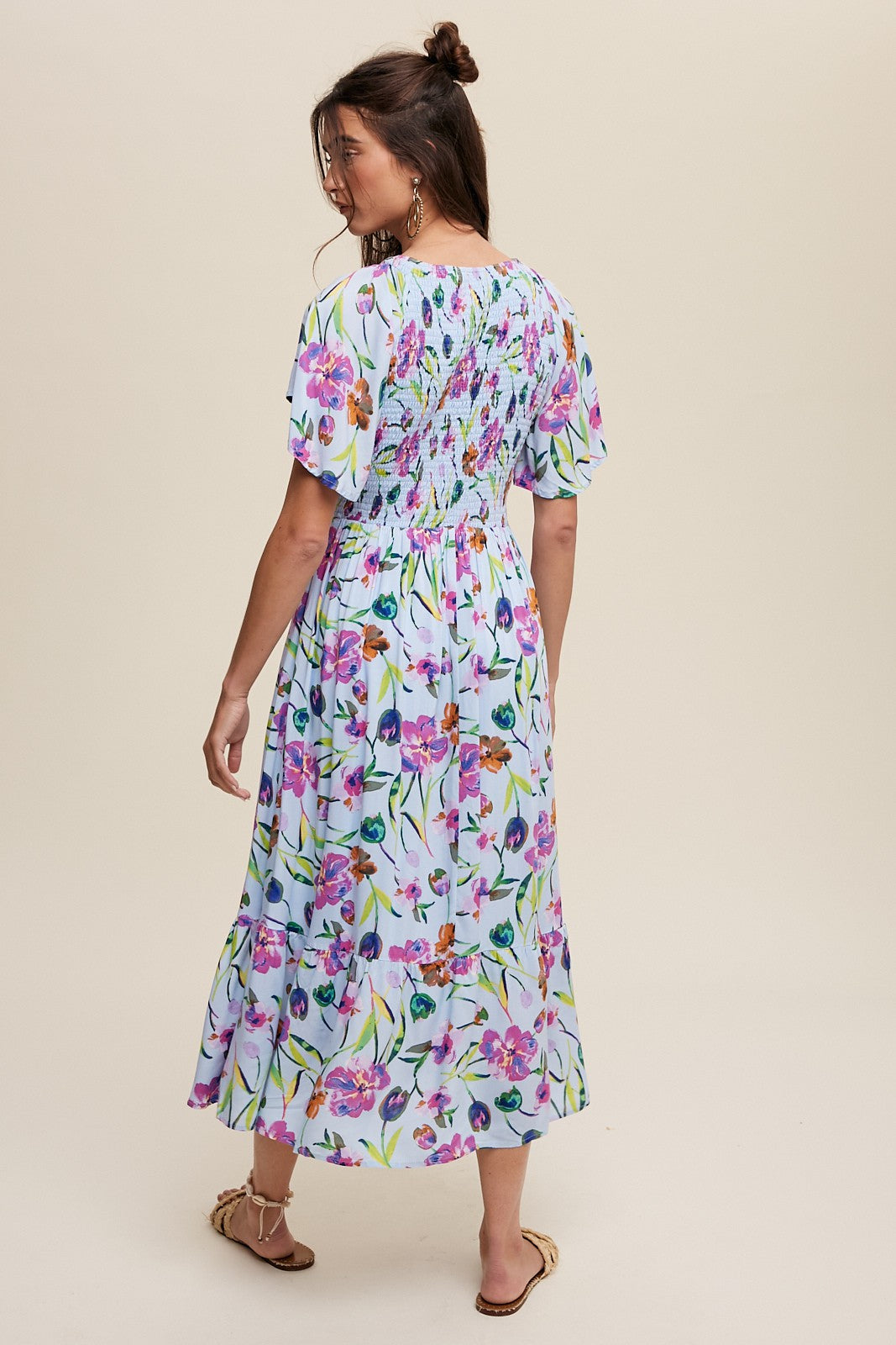 woman wearing a floral maxi dress with short sleeves and a smocked back detail, viewed from the back