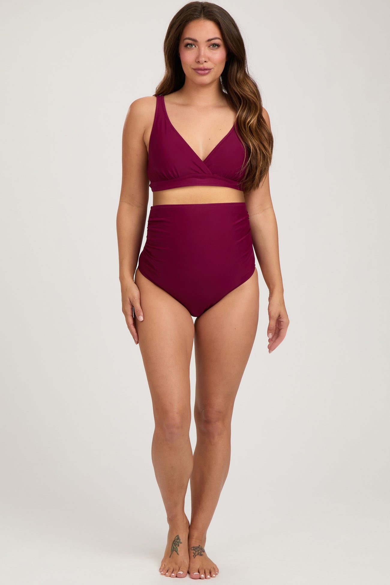 woman wearing a maroon maternity bikini with a wrap-style top and high-waisted bottoms