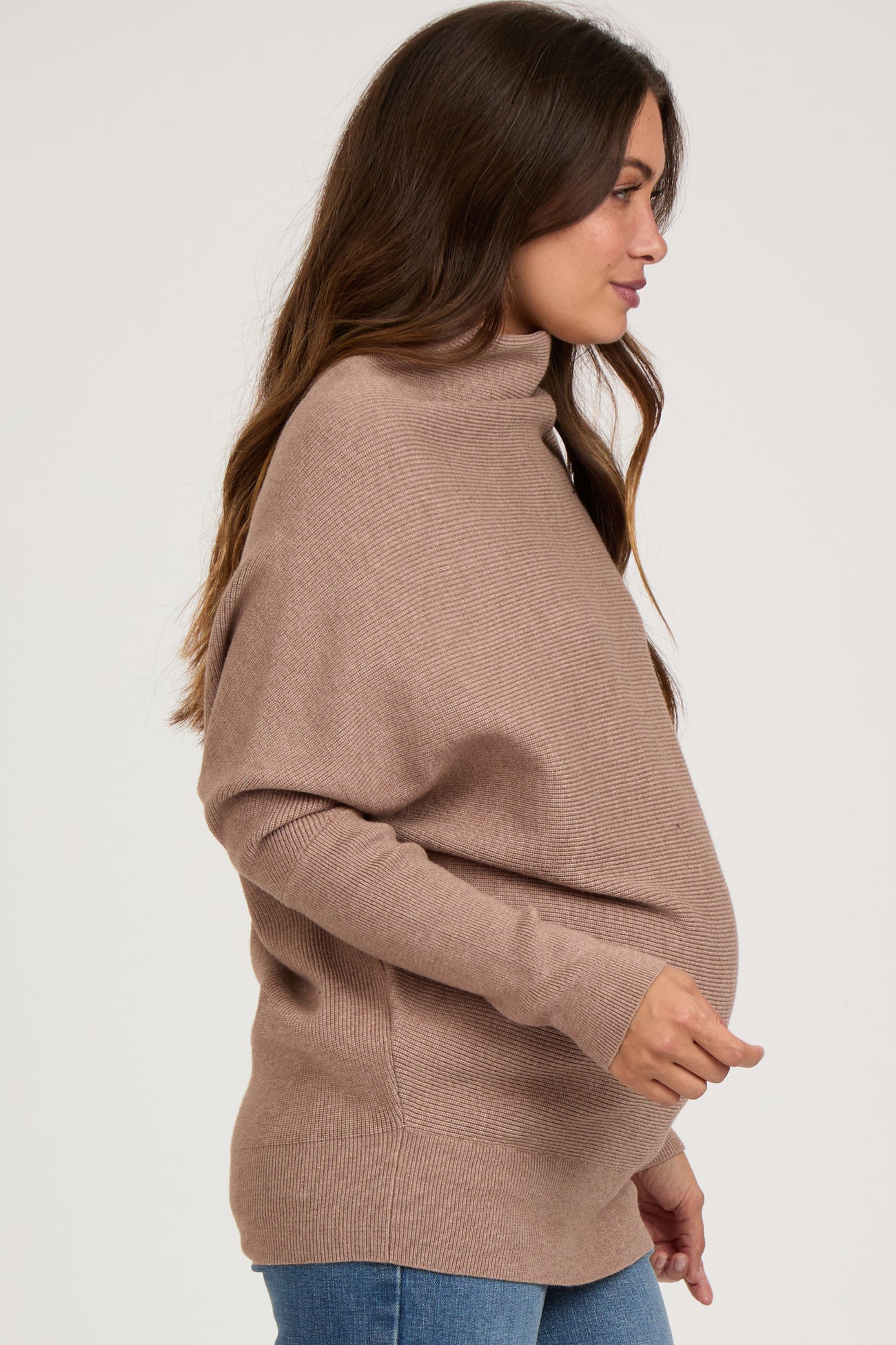 woman wearing a taupe maternity turtleneck sweater and showing her baby bump