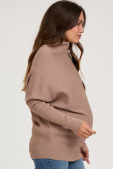 woman wearing a taupe maternity turtleneck sweater and showing her baby bump