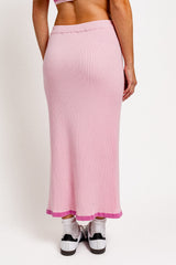 woman wearing a midi ribbed skirt in light pink with a horizontal hem detail in darker pink