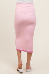 woman wearing a pink ribbed midi skirt with a fitted waistband and a slightly longer hem at the back, styled for maternity wear