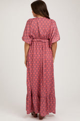 woman wearing a patterned pink maternity maxi dress with a belt and flutter sleeves seen from the back