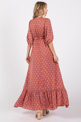 woman wearing a long floral patterned maxi dress with a tiered hem and belt detail, shown from the back