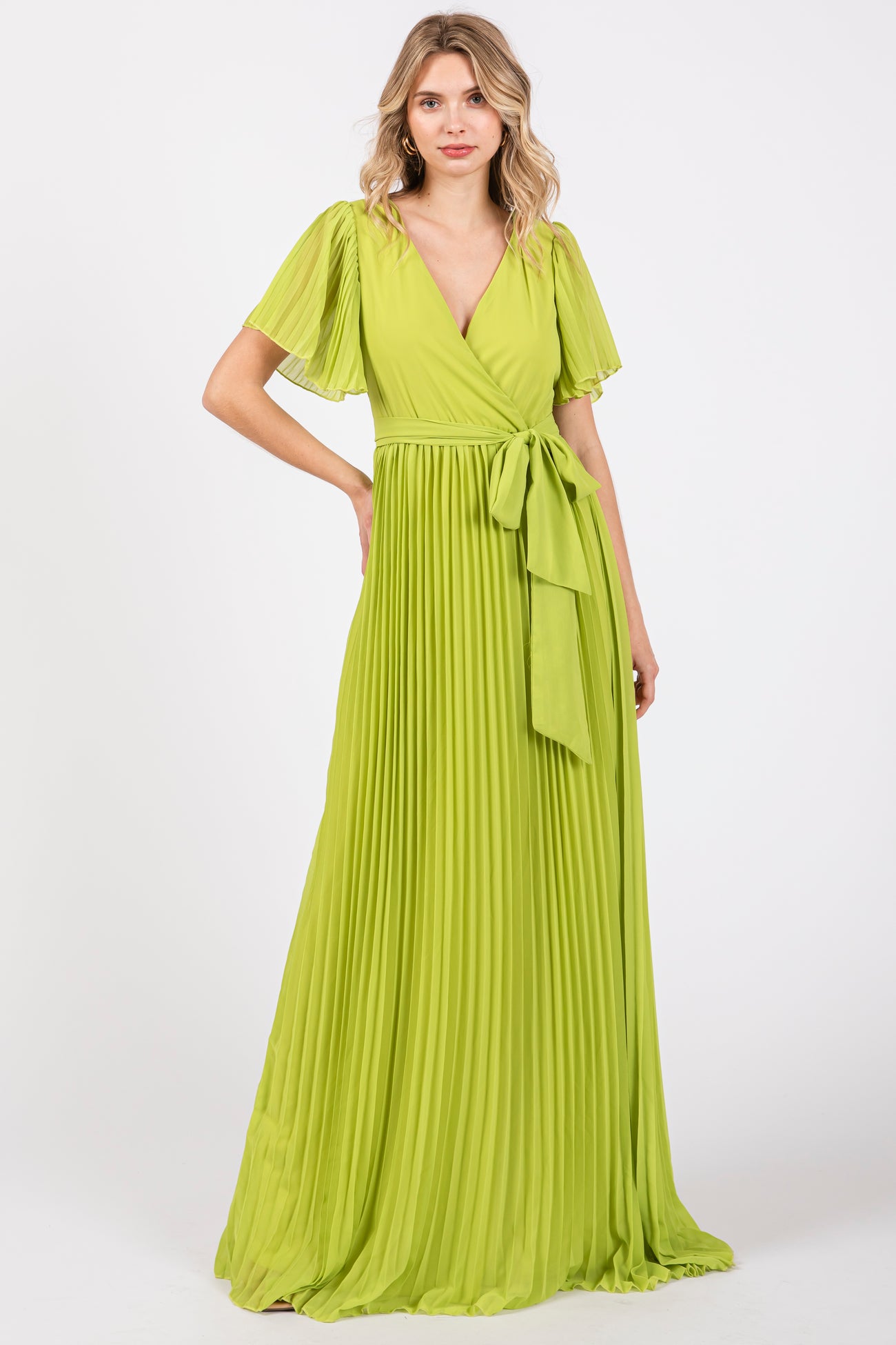 woman wearing a bright green pleated maxi dress with short flutter sleeves and a tie waist