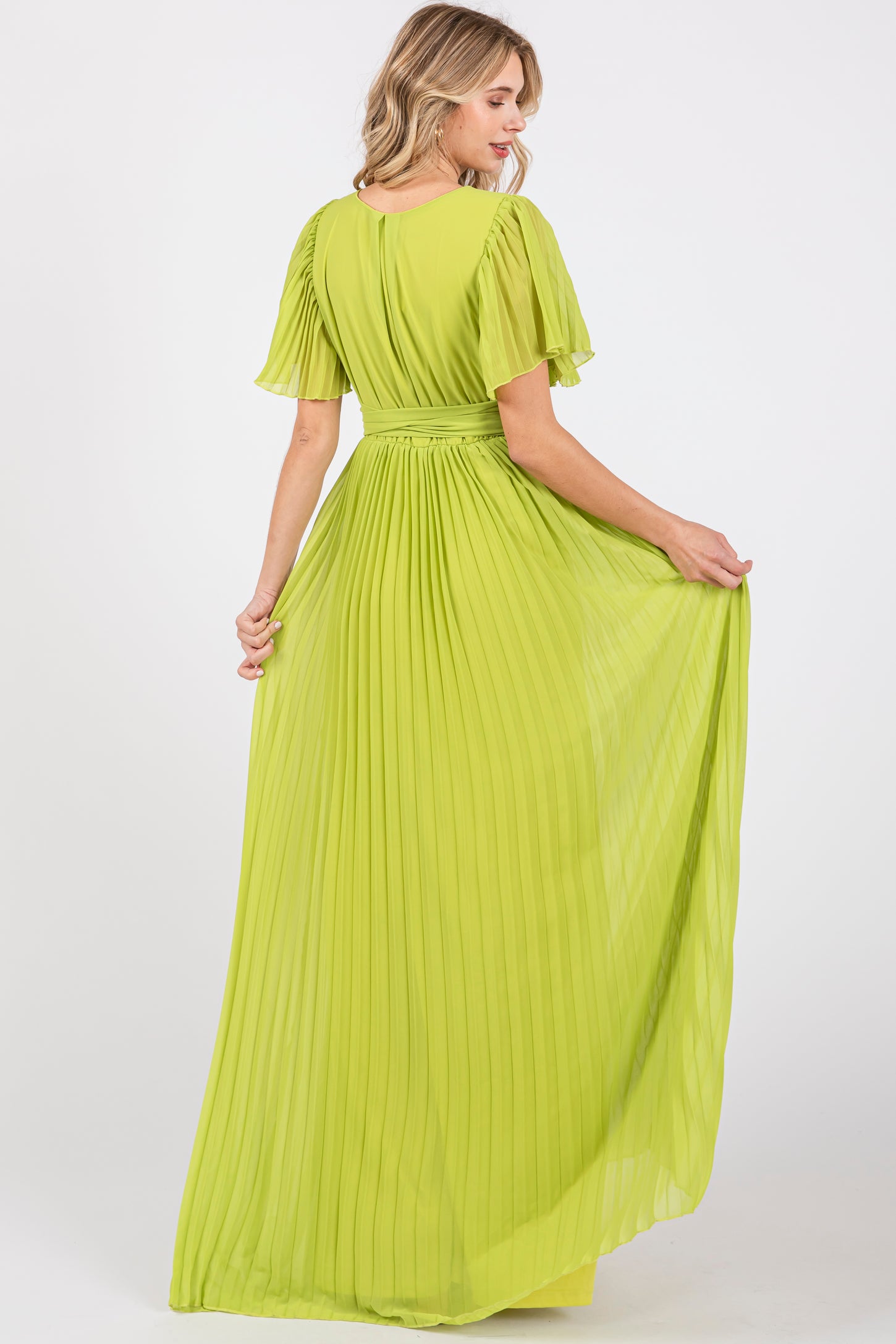 woman wearing a bright lime green pleated maxi dress with short flutter sleeves and a cinched waist