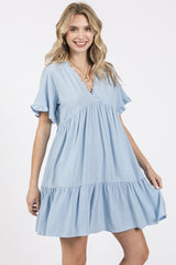 woman wearing a light blue short sleeve dress with a ruffled hem and a plunging neckline