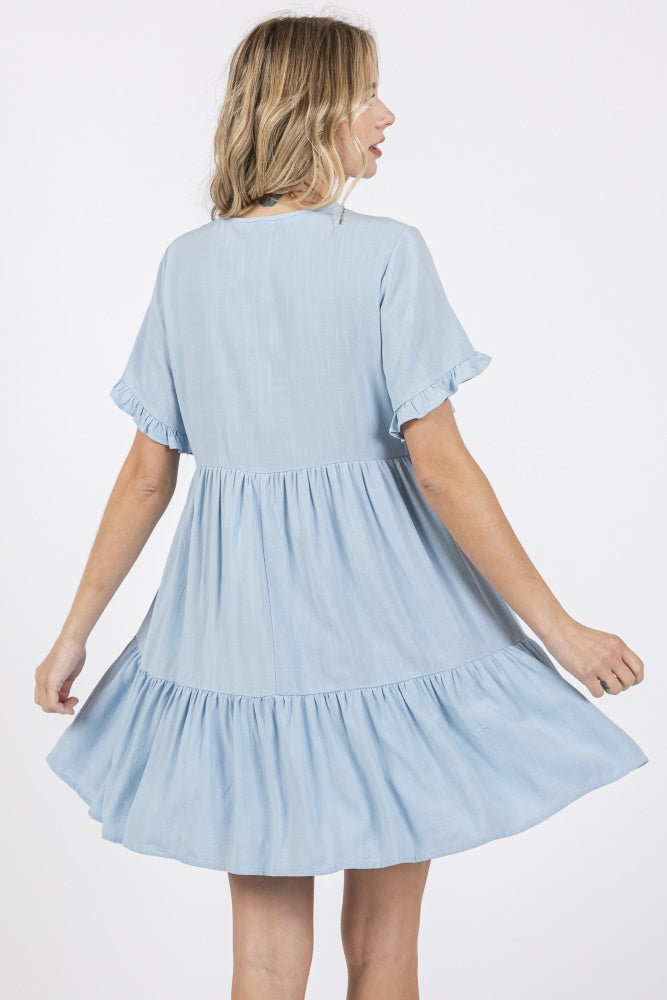woman wearing a light blue relaxed fit dress with ruffled sleeves and a tiered skirt