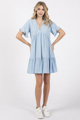 woman wearing a light blue short sleeve tiered dress with ruffled sleeves and a v-neckline