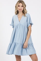 woman wearing a light blue short sleeve tiered dress with a V-neck and ruffle details
