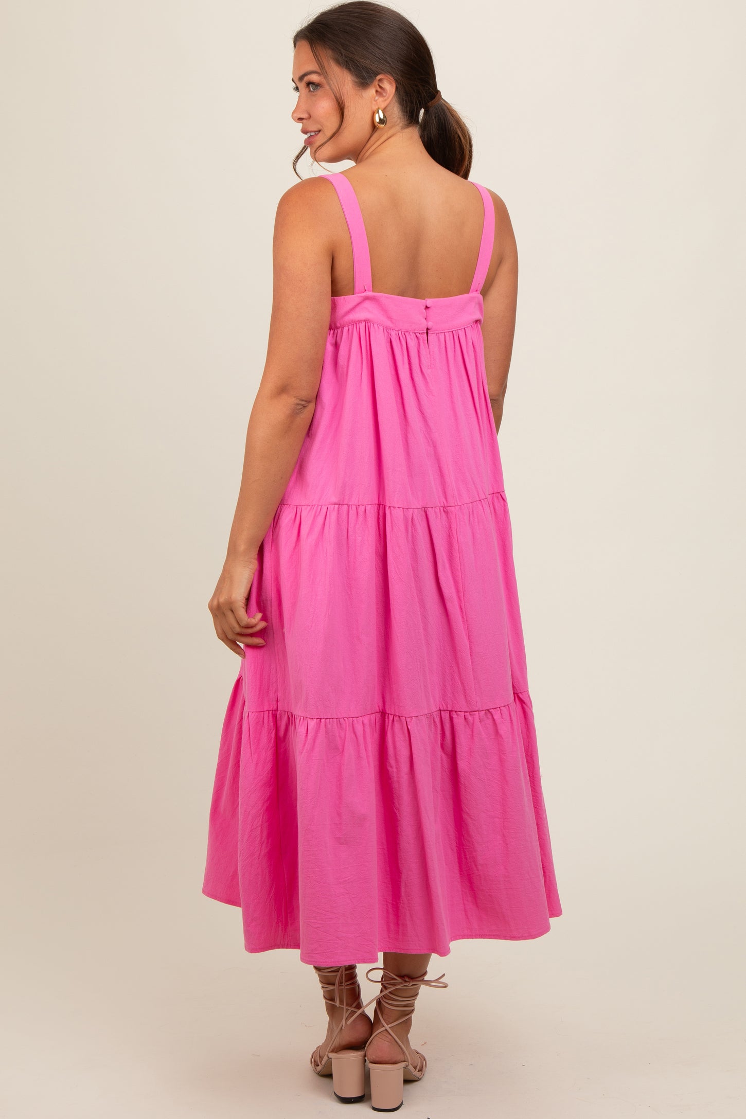 woman wearing a pink tiered maternity dress with adjustable straps and a relaxed fit