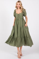woman wearing a green puff sleeve maxi dress with a tie front and side pockets