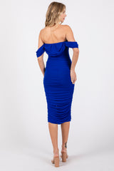 woman wearing a fitted royal blue off-the-shoulder dress with ruched details and a midi length