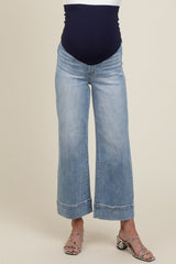 woman wearing light blue wide leg maternity jeans with a navy blue belly panel and silver heeled sandals