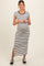 woman wearing a black and white striped maternity maxi dress with short sleeves and a side slit, showing her baby bump
