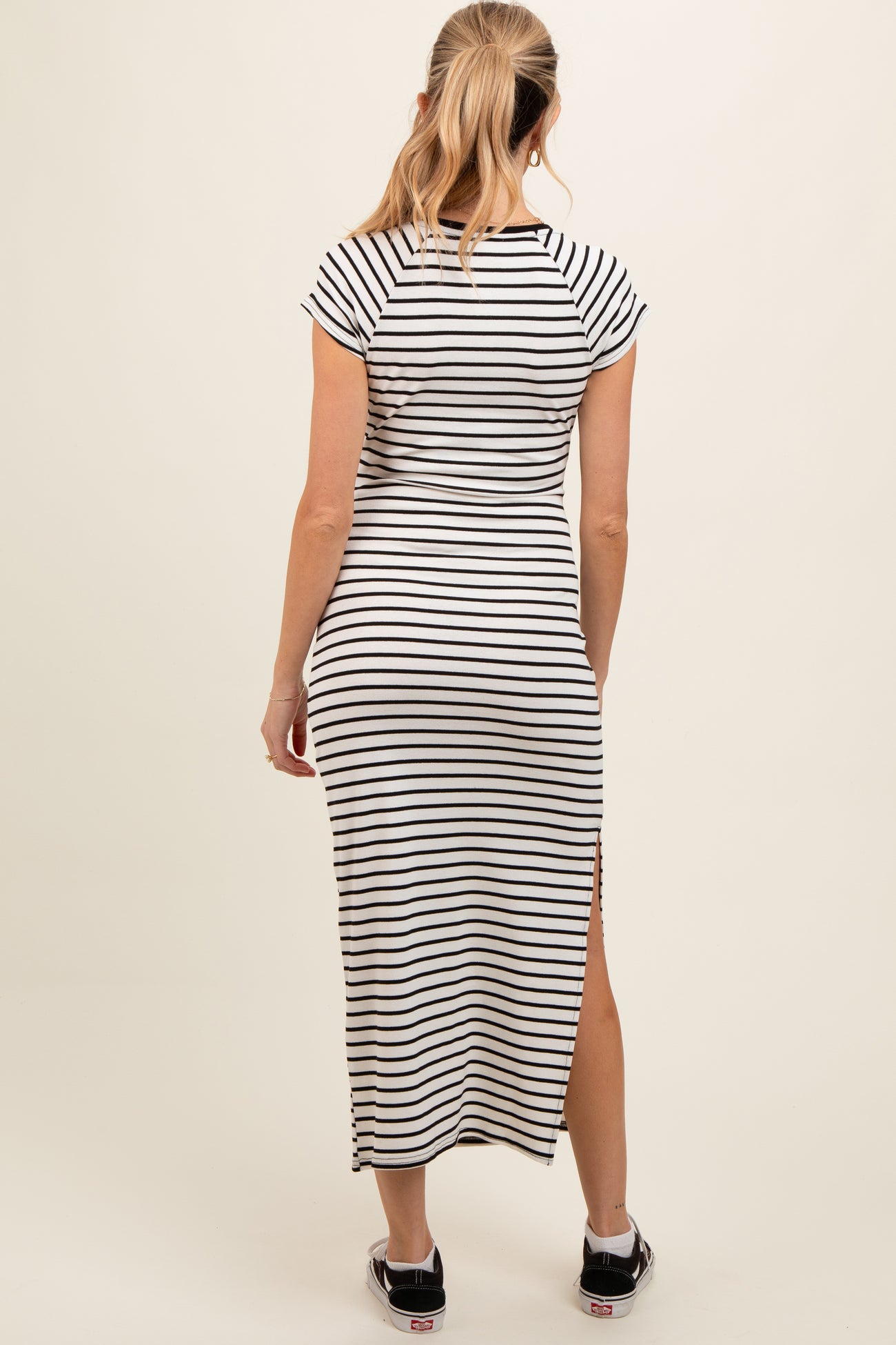 woman wearing a black and white striped maternity maxi dress with short sleeves and side slits