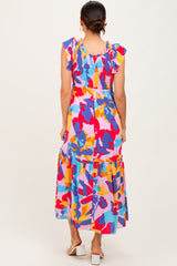 woman wearing a colorful floral maxi dress with ruffled sleeves and a tiered skirt, viewed from the back
