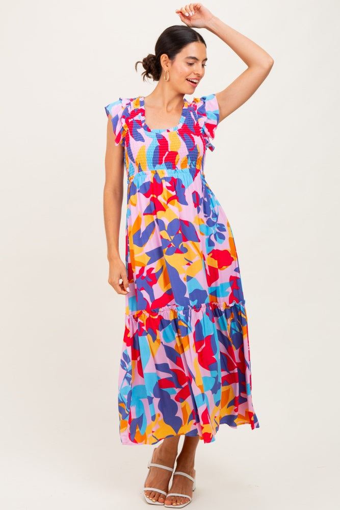 woman wearing a colorful floral maxi dress with ruffle sleeves and a tiered skirt, posing playfully