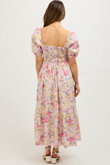 woman wearing a floral maternity maxi dress with puff sleeves and a smocked back, showing her baby bump