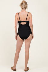 woman wearing a black ribbed one-piece swimsuit with cut-out detail at the back
