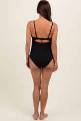woman wearing a black ribbed maternity swimsuit with an open back and adjustable straps, seen from the back