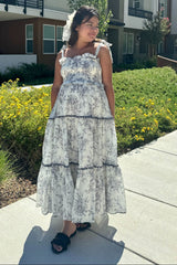 woman wearing a floral maternity maxi dress with ruffled tiers and spaghetti straps, showing her baby bump