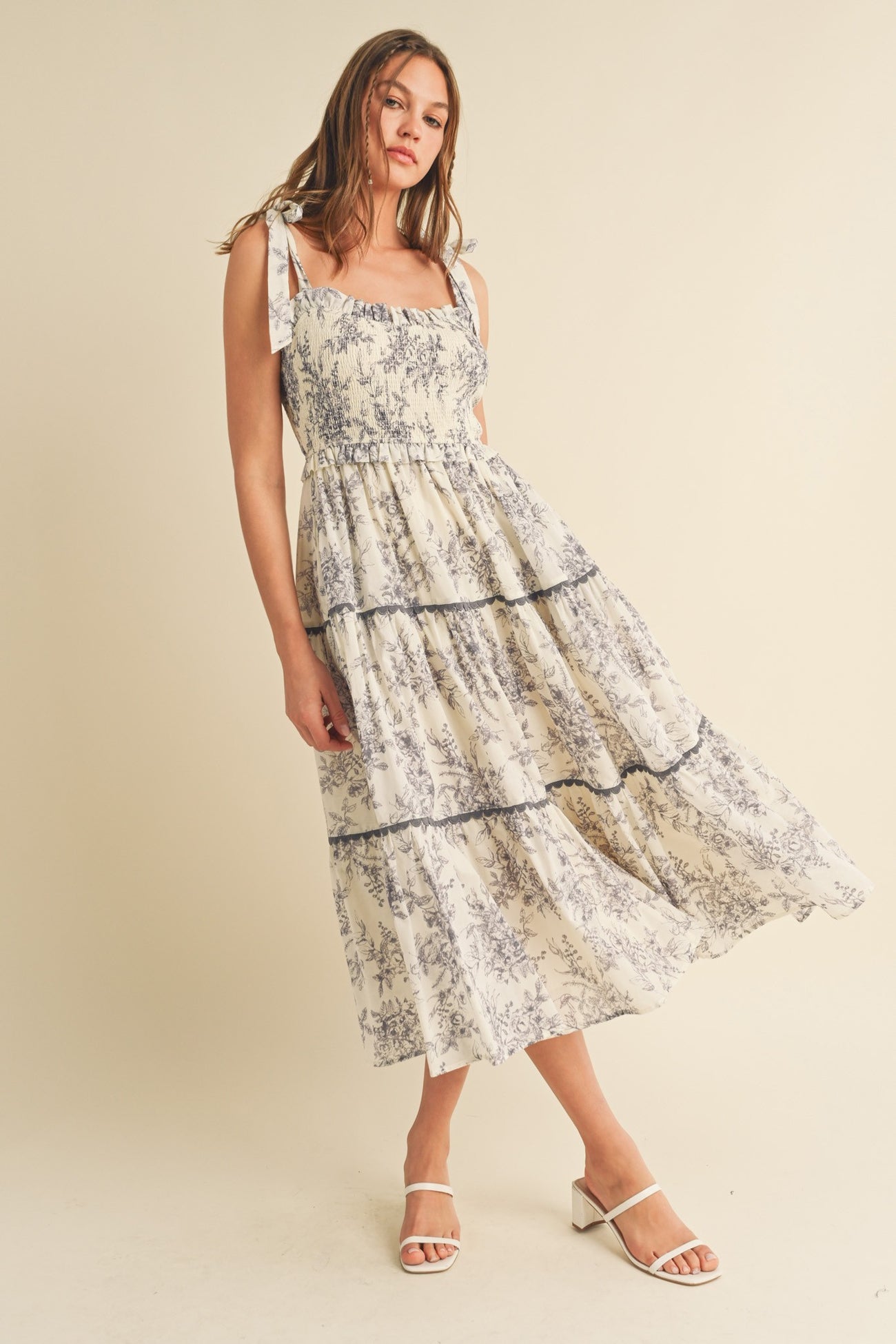 woman wearing a floral print midi dress with tie shoulder straps and tiered ruffle details