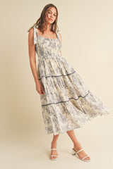 woman wearing a floral print midi dress with tie shoulder straps and tiered ruffle details