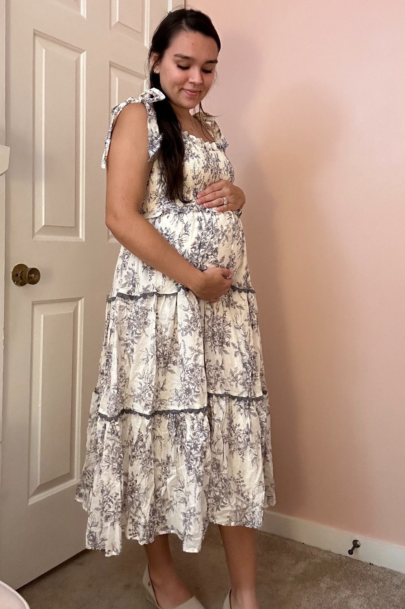 woman wearing a floral print maternity dress with ruffled tiers and holding her baby bump